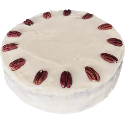 Hummingbird cake with pale cream cheese frosting and a ring of pecan halves on top.